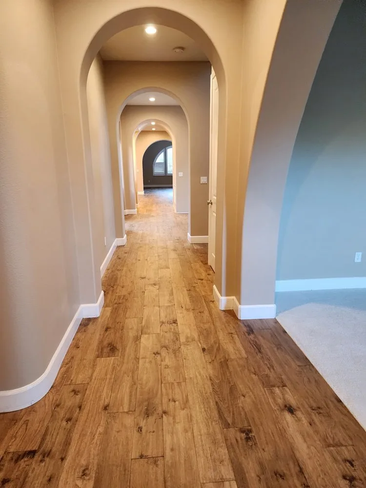 Wood-look plank flooring in an arched hallway by The Flooring Design Center