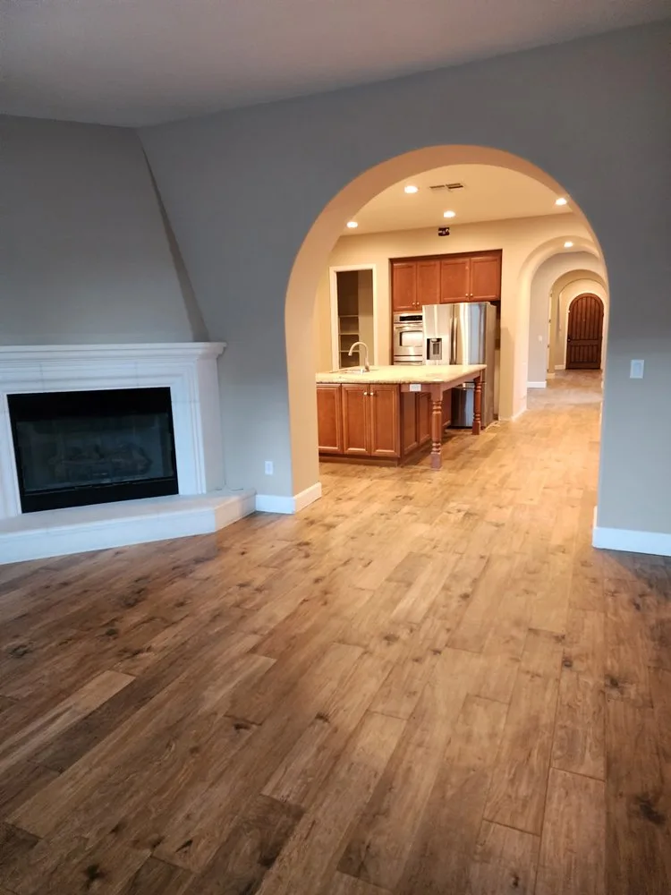 Open-concept wood-look plank flooring through living room and kitchen by The Flooring Design Center